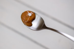 Peanut butter on spoon with pill